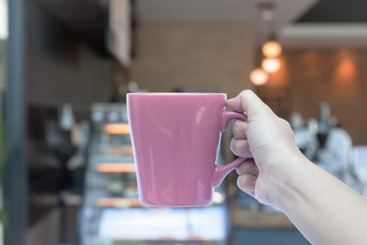 Woman hands holding coffee cup with blurred coffee shop, stock photo