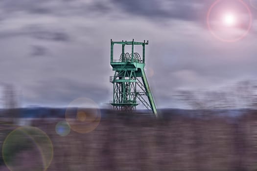 Image with Lens Flare Effect and Blur: Old Winding Tower Industrial monument in the Ruhr area in front of sky with clouds Twilight. .