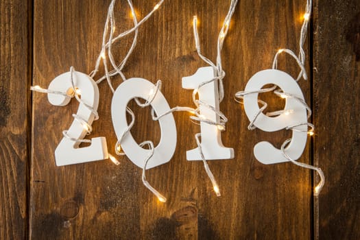 2019 with string of lights on rustic wooden background