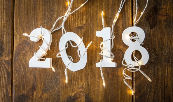 2018 with string of lights on rustic wooden background