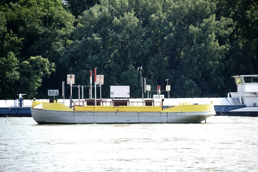 The side view of a container ship passing an anchored cutter with signs.