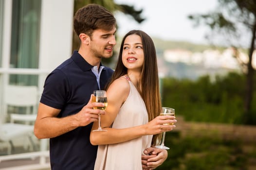 Young couple tasting wine near by the pool on a hotel