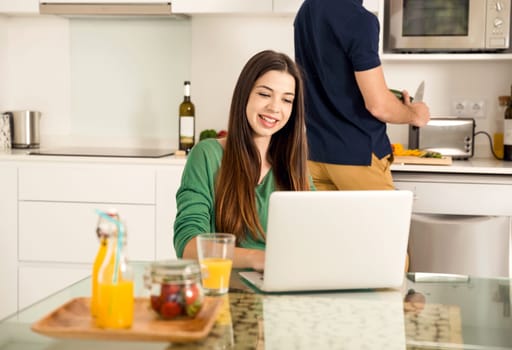Young couple on the kitchen follow a recipe by tablet and cooking