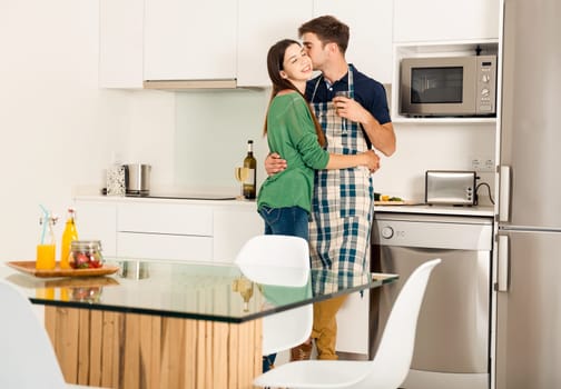 Young couple on the kitchen follow a recipe by tablet and cooking