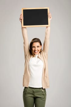 Beautiful and happy woman holding and showing a chalkboard very high