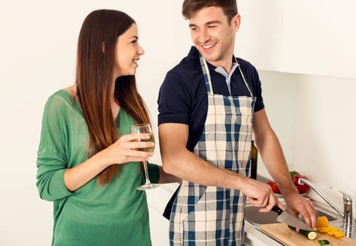 Young couple on the kitchen follow a recipe by tablet and cooking