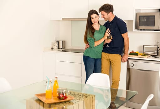 Young couple on the kitchen follow a recipe by tablet and cooking