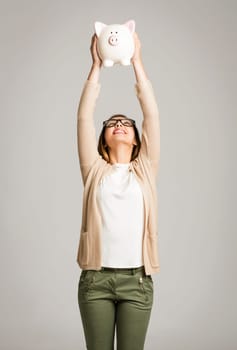 Beautiful and happy woman holding a piggy bank and making thumb up