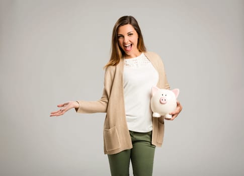 Beautiful and happy woman holding a piggy bank and making thumb up