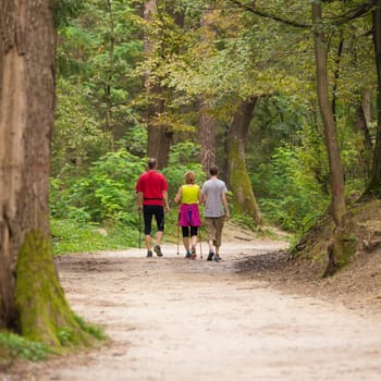Family hiking on trail in woods and talking.