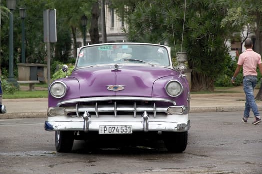 Old classic american cars drived along the street at the Havana old town