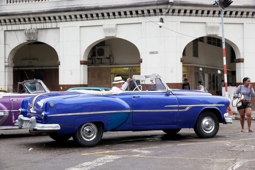 Old classic american cars used as taxi is drived along the street at the Havana old town