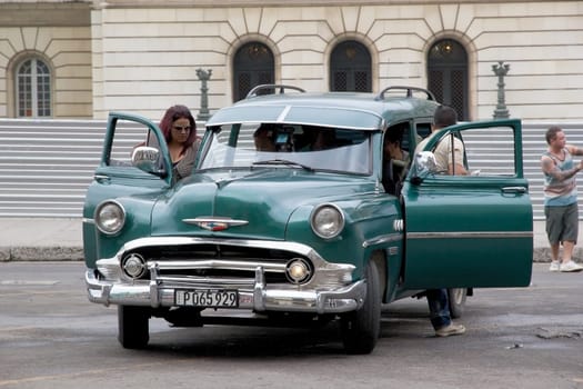 Old classic american cars drived along the street at the Havana old town