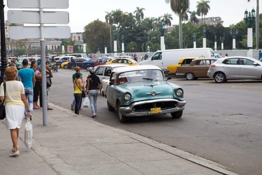 Old classic american cars drived along the street at the Havana old town