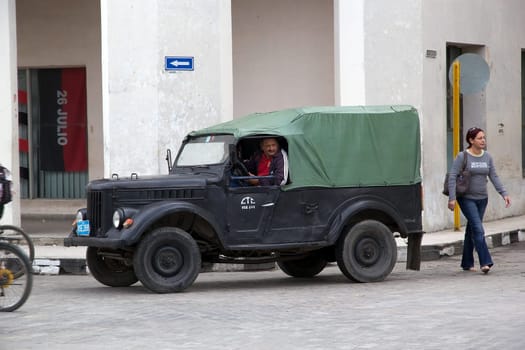 Cuban man is driving the old american classic car along the street in Santa Clara, Cuba