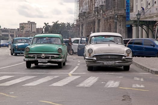 Cuban men are driving a old classic american cars along the street in Havana, Cuba