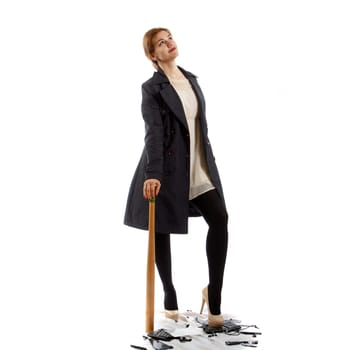 A young lady with a baseball bat standing on a broken keyboard