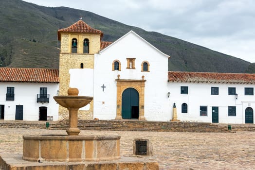 View of the colonial fountain and church on the main plaza of Villa de Leyva, Colombia
