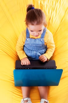 Portrait of a child  sitting on a bean bag with laptop. Isolated on white.