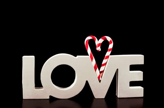 large letters LOVE and Valentine Heart made from Christmas candies isolated on black background