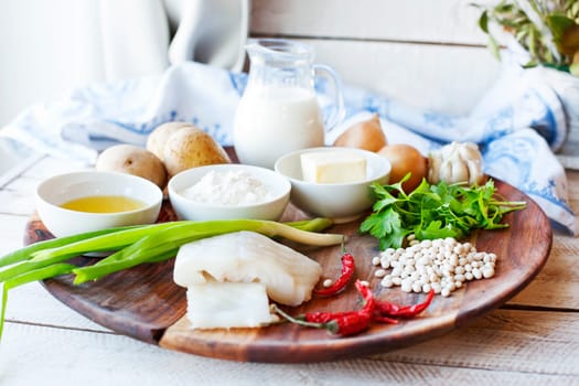 Wooden plate with ingredients from fish and vegetables for cooking cutlets with mashed potatoes