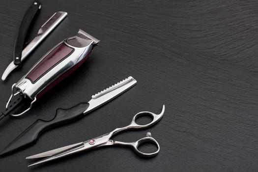 Barber shop equipment on Black background with place for text.  Professional hairdressing tools. Comb, scissor, clippers and hair trimmer isolated.