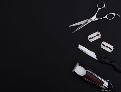 Barber shop equipment on Black background with place for text.  Professional hairdressing tools. Comb, scissor, clippers and hair trimmer isolated.