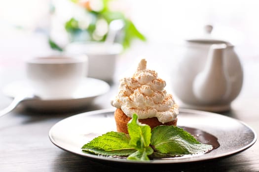 Breakfast time . Tea and cake with cream, garnished with mint leaves
