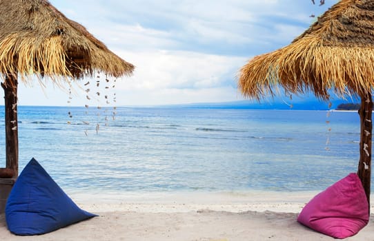 Straw umbrellas and bean bag at the seashore.