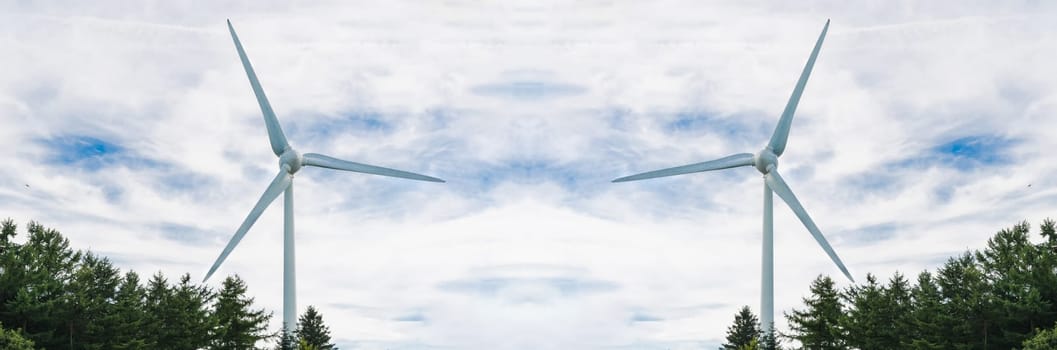 Two wind turbines with overcast skies with rays of light.