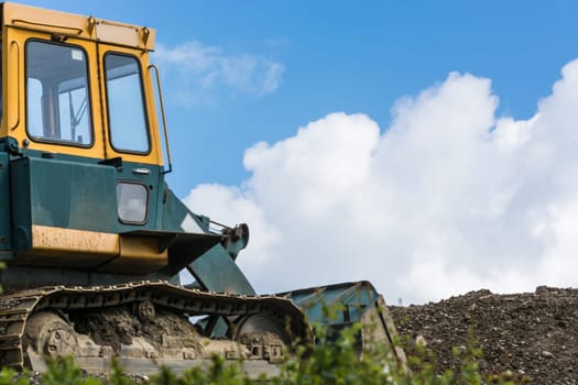 Excavator construction machine on a construction site in the background a blue sky.