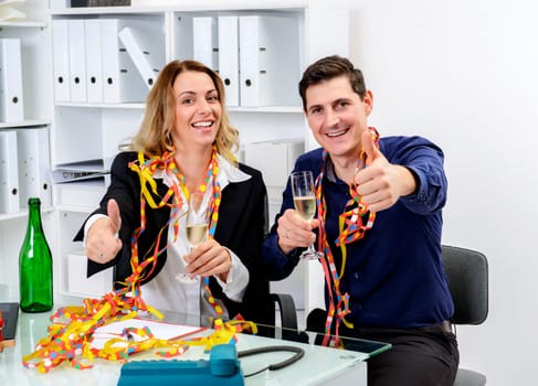 young businessman and businesswoman celebrating together in the office
