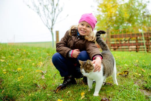 little girl playing with cat in front of nature background