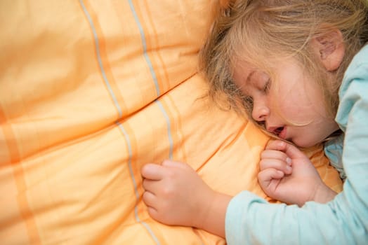 little girl is sleeping on orange pillow