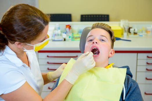 teenager is treated by female dentist in dental surgery