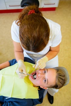 teenager is treated by female dentist in dental surgery