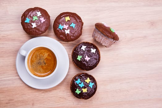 chocolate muffins with cup of coffee on wooden ground