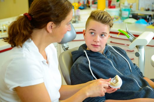 teenager is treated by female dentist in dental surgery