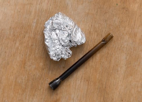 marijuana in tin foil with pipe on wooden table