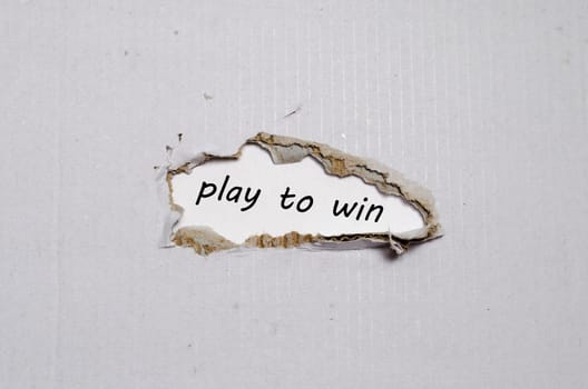 The word play to win appearing behind torn paper