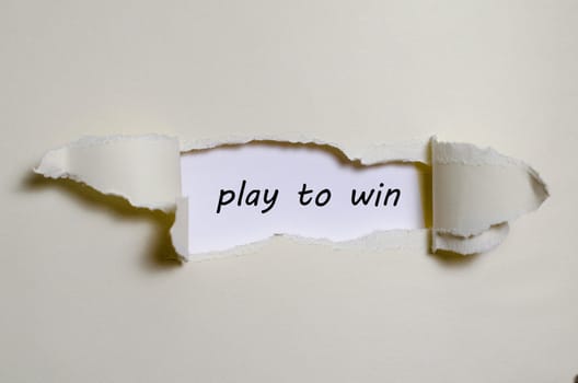 The word play to win appearing behind torn paper