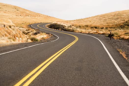 Two Lane blacktop road leads through scenic countryside