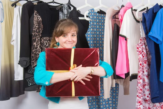 Happy young girl has received a welcome gift in the background hang things on hangers