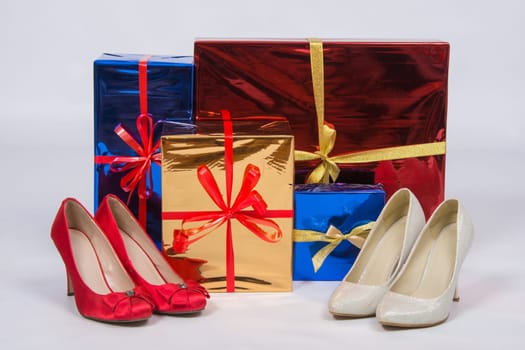 Red and white female shoes with high heels, standing near boxes with gifts