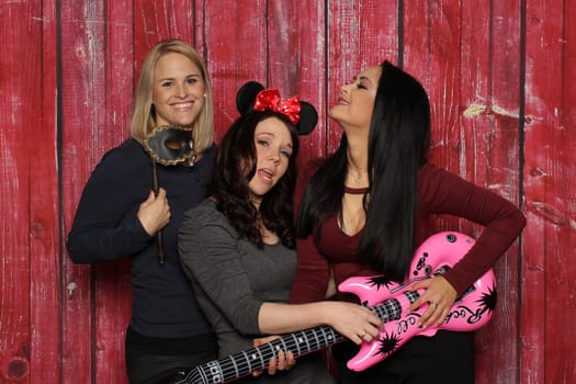 Girl trio fools around in front of a photo booth