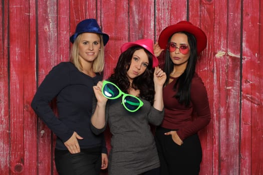 Cool girls with glasses and hats in front of a photo booth