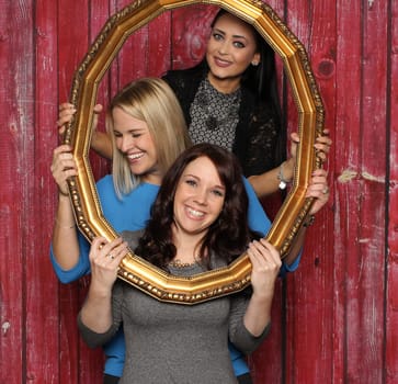 3 girls with picture frames in front of a photo booth