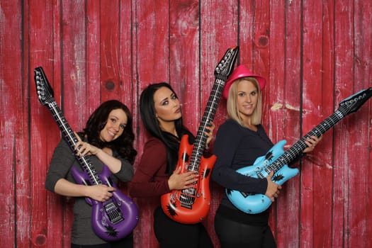 Three young women play on plastic guitars