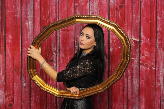 Young woman looks through a frame against a red background