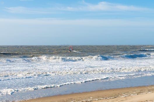 single wind surfer braving the waves on a rough north sea